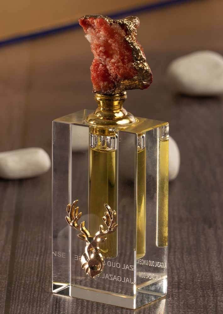 مسك احمر في زجاجة عليها شعار غزال معدني من متجر عاج الغزال