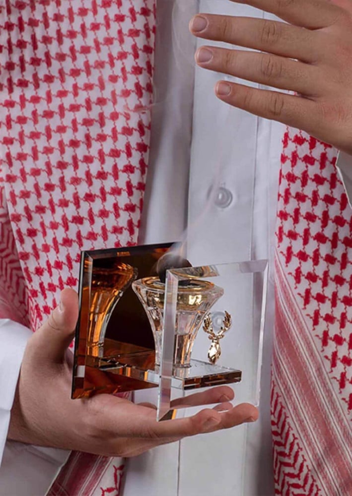 رجل سعودي يحمل مبخرة قزاز كريستال فيها بخور من متجر مباخر عاج الغزال