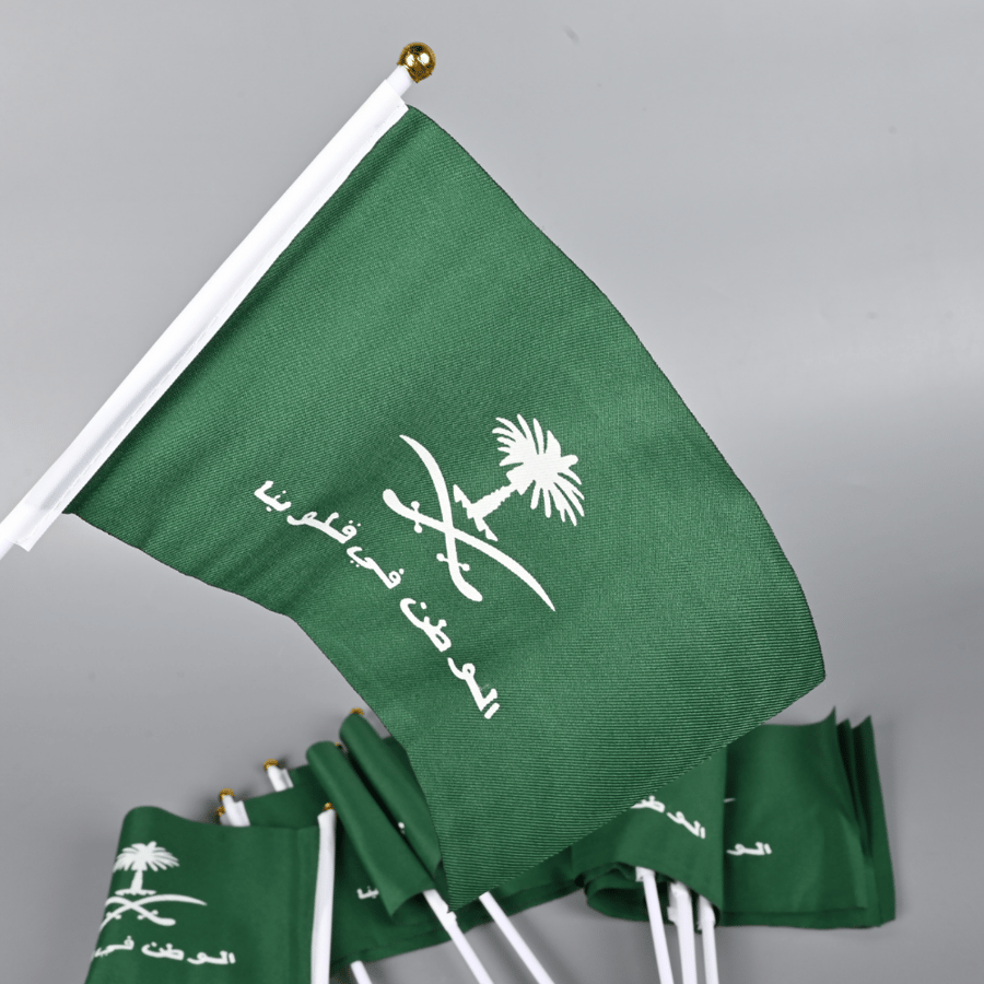 طقم 12 علم قماش لليوم الوطني مقاس 14×21 سم - عبارة الوطن في قلوبنا مع سيفين ونخلة