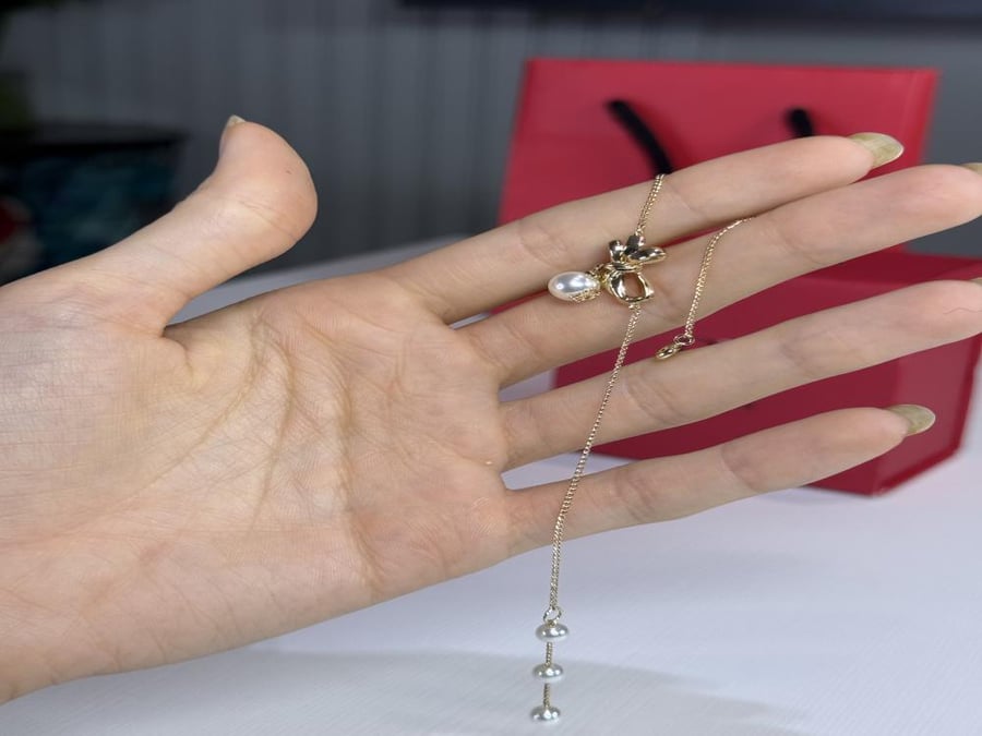 اسوار كارولينا مزين على شكل باو ذهبي مع لولو متدلي carolina Herrera gold bow pearl bracelet