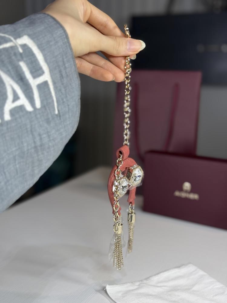 تعليقة اجنر باللون الوردي المرصع بالاحجار على شكل حذوه من الجلد الوردي Aigner pink charm with stones and tassels