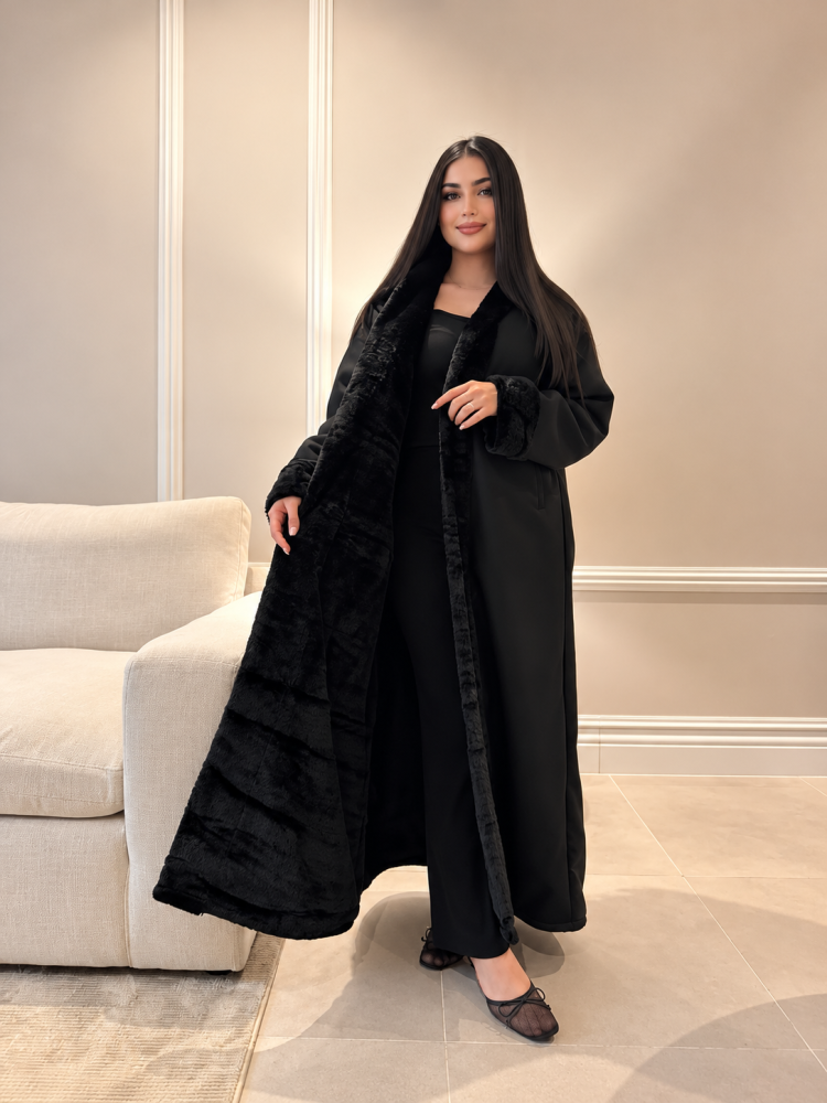 عباية شتوية نسائية سوداء فاخرة بغطاء رأس وفرو أسود ناعم على المقدمة والأكمام بتصميم طويل وواسع | عبايات شتاء دافئة وأنيقة للخروج والسفر