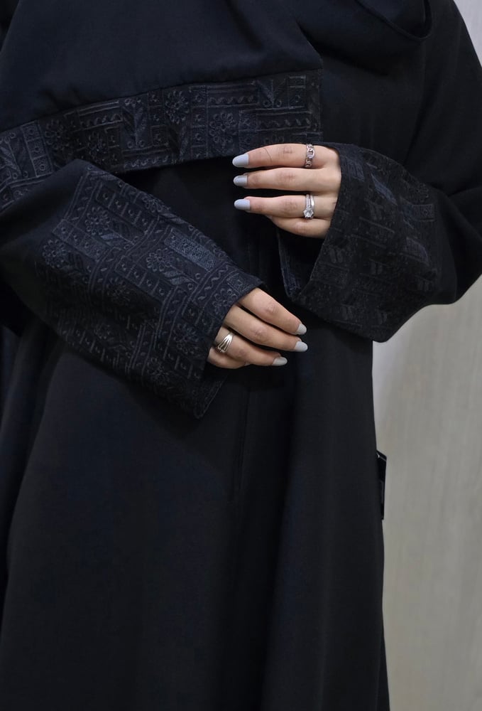 Black abaya, elegant fabric, standing with a blunt belt