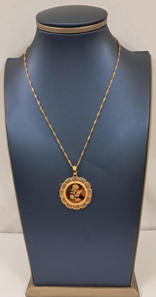 A necklace with a circular pendant with a carved flower design