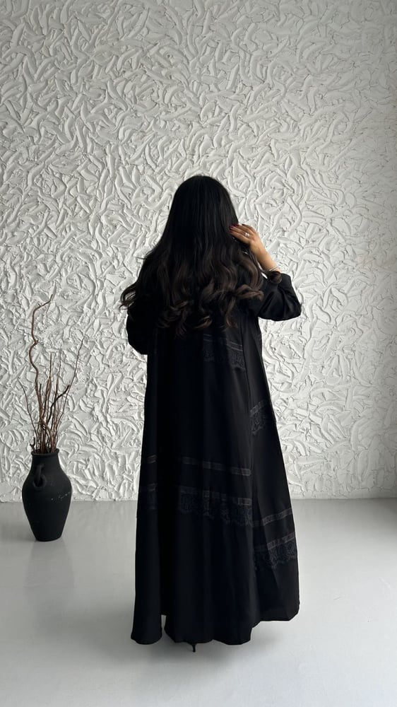 امرأة ترتدي عباية سوداء بتفاصيل دانتيل أنيقة من الخلف