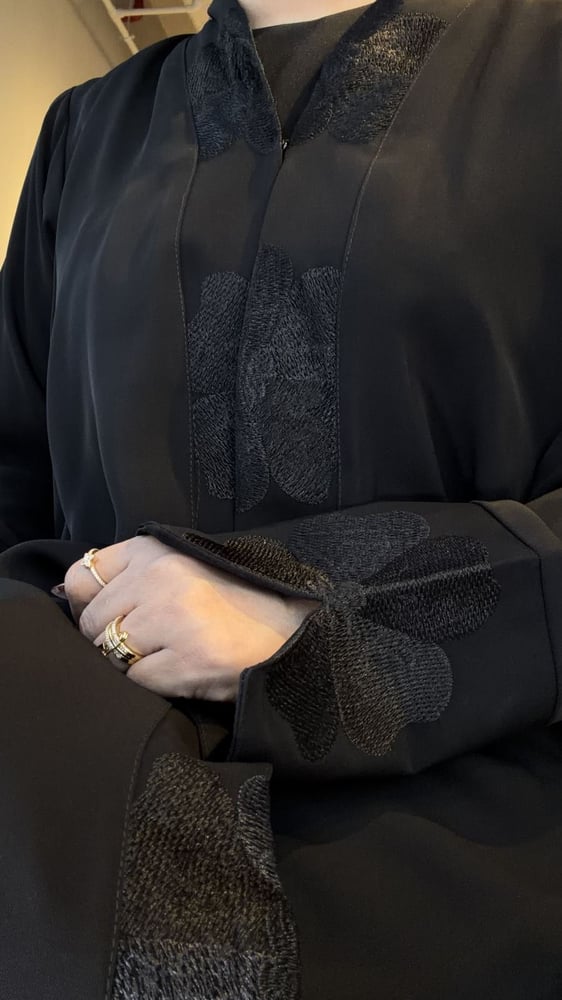 عباية سوداء مطرزة من الأمام بتفاصيل زهرية على الأكمام والواجهة