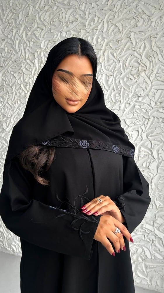 عارضة ترتدي عباية سوداء بتطريز ريش