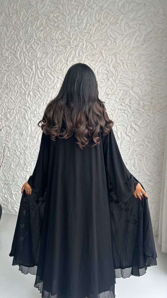 امرأة ترتدي عباية سوداء شفافة من الخلف