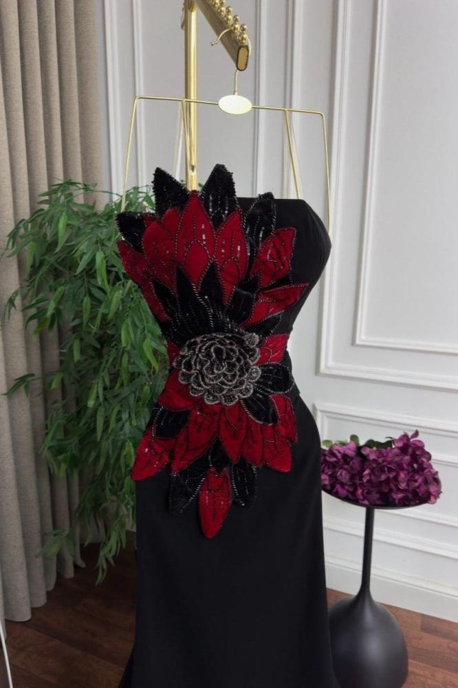 فستان سهرة أسود بزهرة حمراء كبيرة وذيل