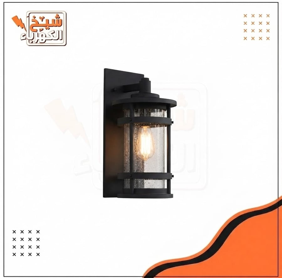 أبليك جداري خارجي أسود بتصميم فانوس أسطواني معلق بزجاج مموج وأشرطة حماية أفقية يحيط بلمبة دافئة، يمنح إضاءة محيطية دافئة ومميزة للواجهات والمداخل الخارجية