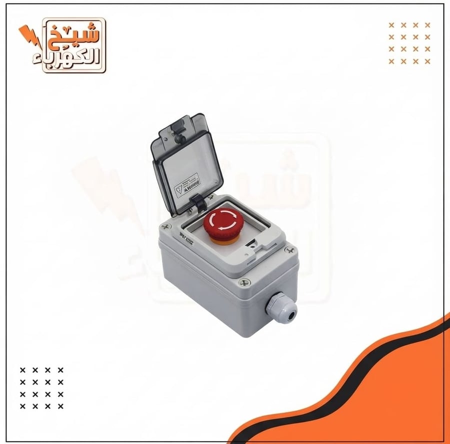 مفتاح إيقاف طوارئ صناعي (زر طوارئ أحمر بارز بنمط الفطر للضغط) موضوع داخل صندوق حماية رمادي متين مزود بغطاء شفّاف مفصلي مقاوم للعوامل الجوية وقرص توصيل كابلات سفلي، مصمم لقطع التيار الكهربائي السريع والآمن في حالات الطوارئ بالمنشآت التجارية والصناعية