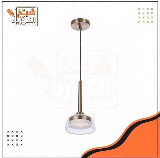 إضاءة معلقة بتصميم عصري أنيق. تتكون من قاعدة سقفية وسلك تعليق دقيق، وجسم معدني بلون برونزي يمتد لأسفل وينتهي بعنصر إضاءة محاط بغطاء زجاجي شفاف بنقاط بيضاء داخلية دقيقة. تتميز بلمبة إضاءة دافئة مدمجة وناشر زجاجي سفلي