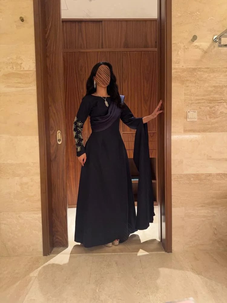 فستان سهرة كحلي بأكمام طويلة وتطريز ذهبي مع وشاح درابيه مائل وتنورة انسيابية