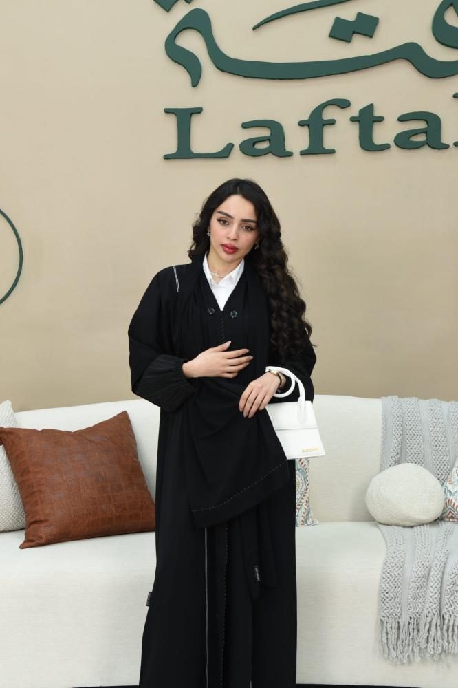 عباية كريب يزينها أزرار وخطوط بيضاء أنيقة