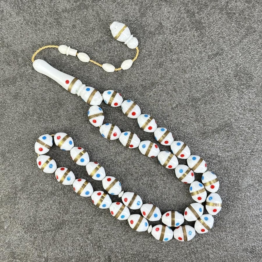 A prayer bead made of camel bone, decorated with synthetic coral.