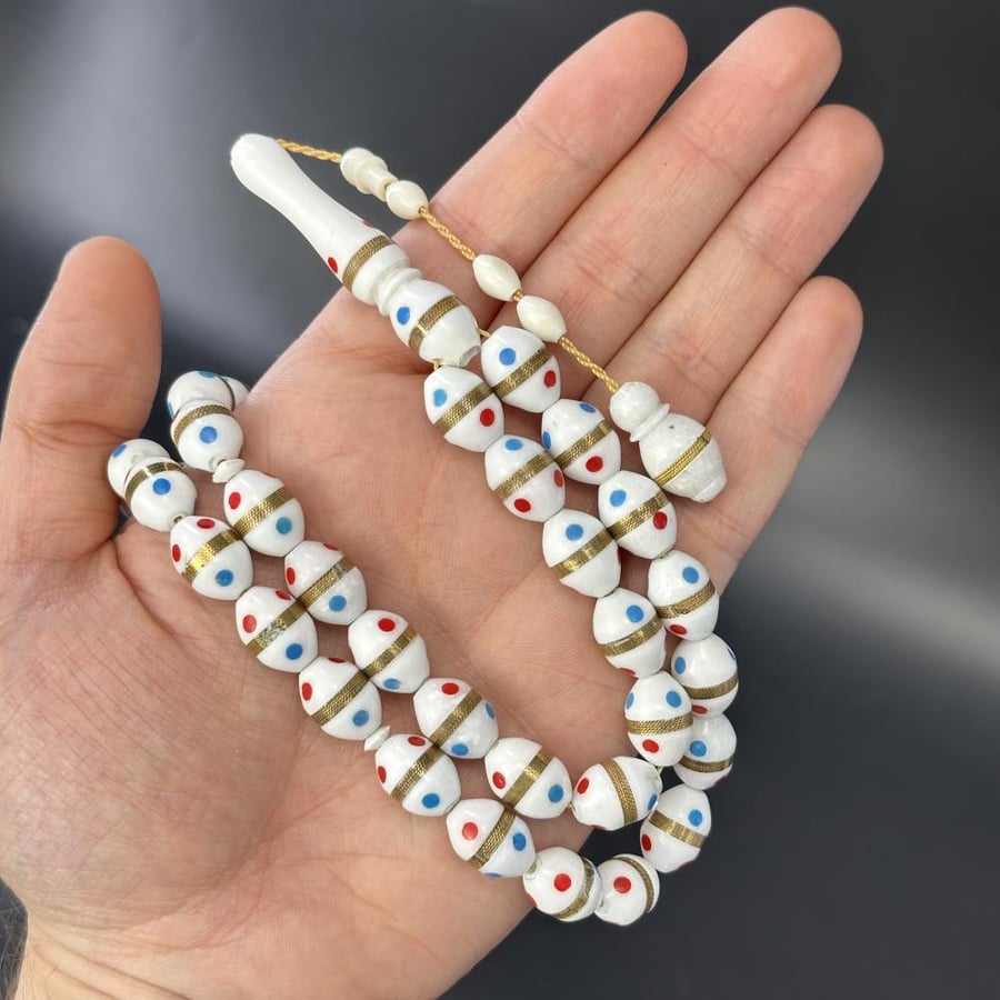 A prayer bead made of camel bone, decorated with synthetic coral.