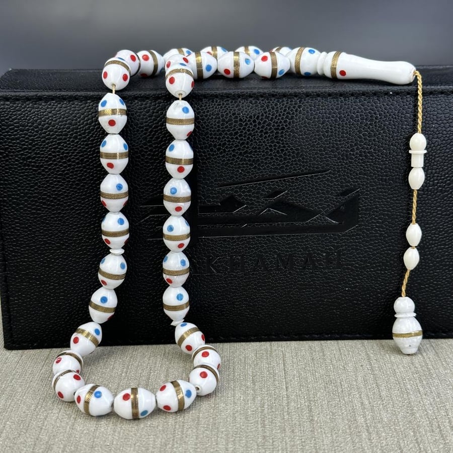 A prayer bead made of camel bone, decorated with synthetic coral.