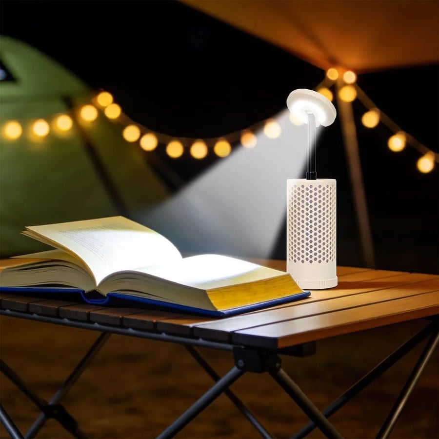 إضاءة لمبة تخييم LED على طاولة تخييم مع كتاب مفتوح تظهر بإضاءة مشرقة