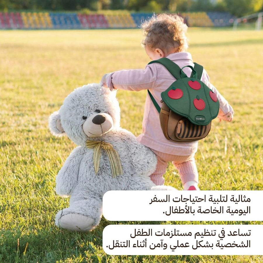 طفل يحمل حقيبة أطفال بوليستر خضراء مع تصميم تفاح يضعها على كتفه بجانب