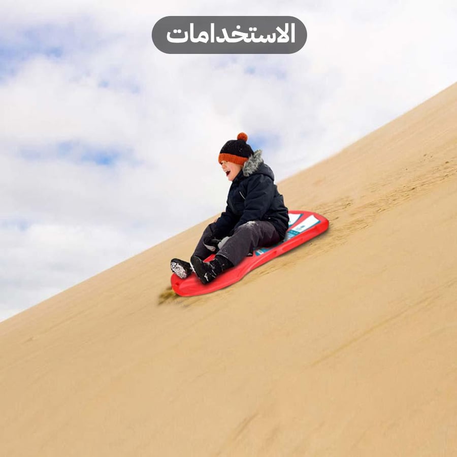طفل يستمتع بالتزلج على الكثبان الرملية باستخدام زلاجة السنيدي الحمراء