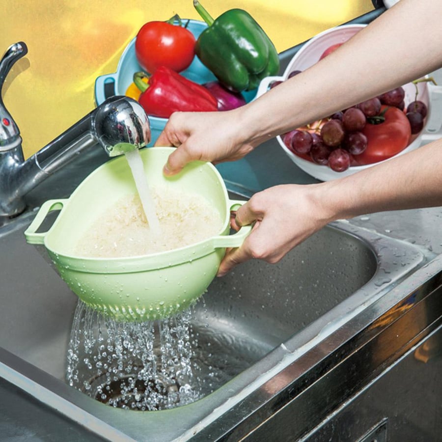 مصفاة خضراء فاتحة تستخدم لتصفية الأرز والخضروات تحت الماء الجاري في