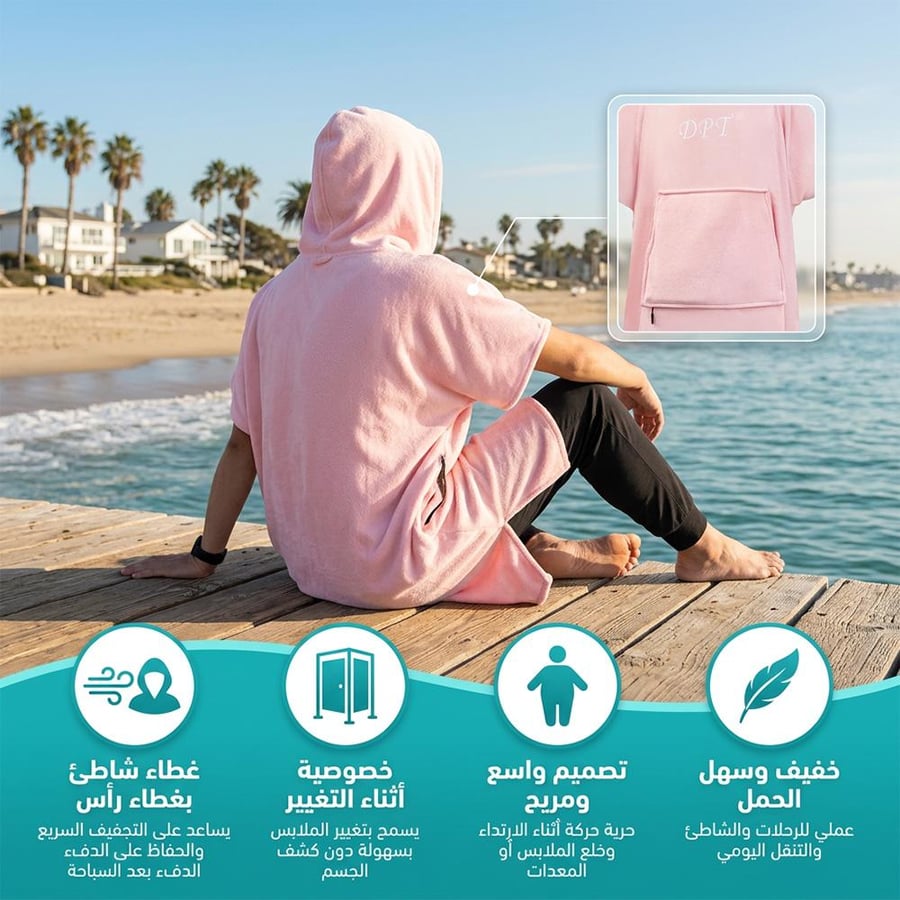 شخص يجلس على الشاطئ مرتدي ا رداء زهري واسع مع هودي يظهر التصميم