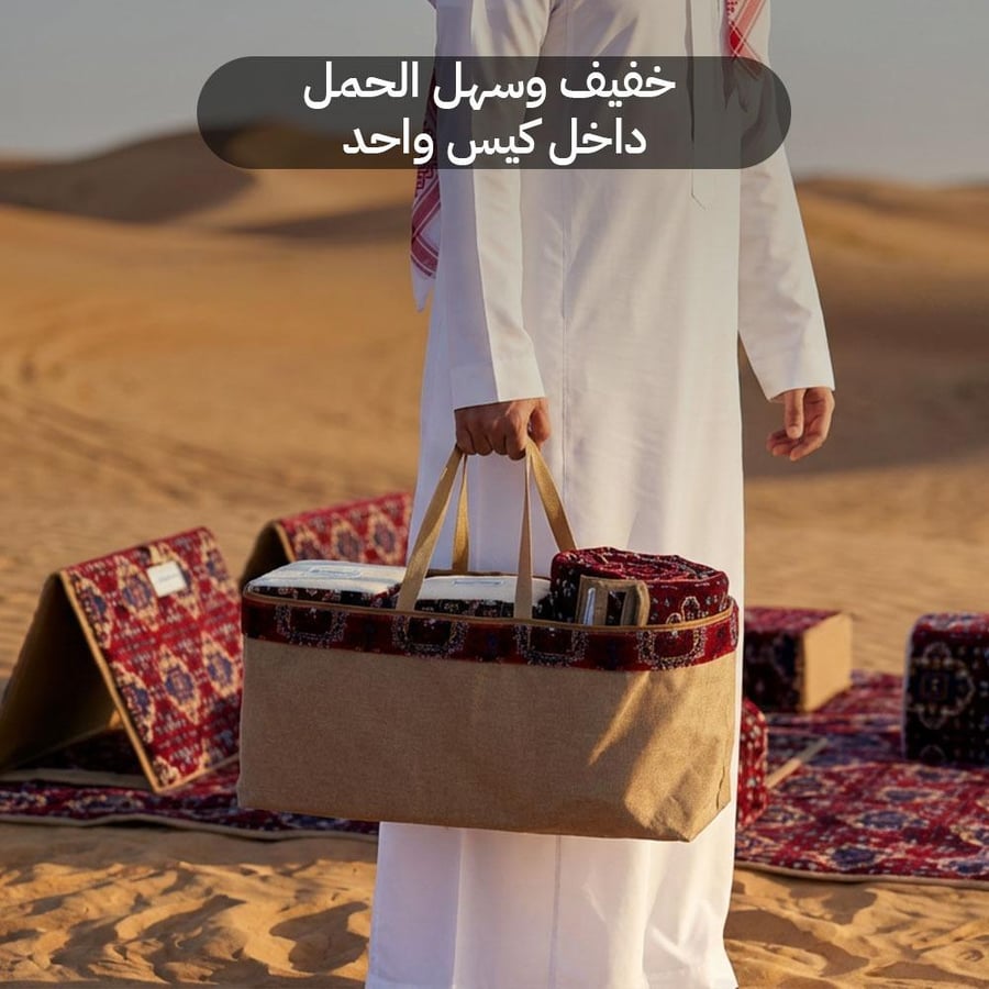 شخص يحمل شنطة نقل تحتوي على جلسة كشتة فاخرة بلون أحمر روفا في الصحراء
