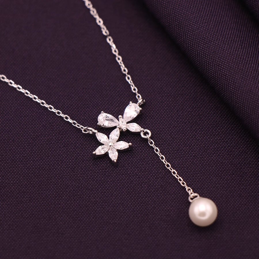 لقطة قريبة لعقد فضة بزهور وتعليقة بيضاء متدلية