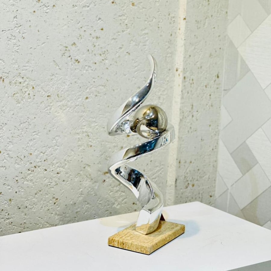 A piece of artistic decor with a modern spiral design embodying fluidity and balance in an elegant style. Made of shiny metal in silver color 40×18×10 cm