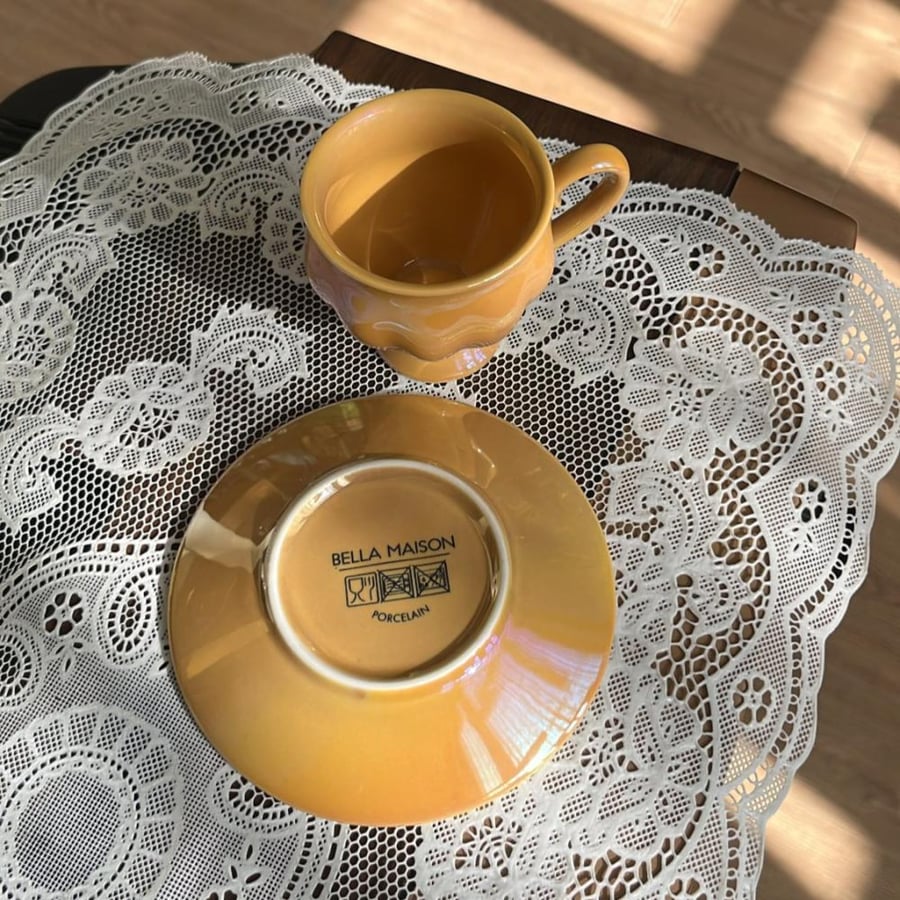 Bella Maison Clara porcelain coffee cup in mustard color features a glossy surface.