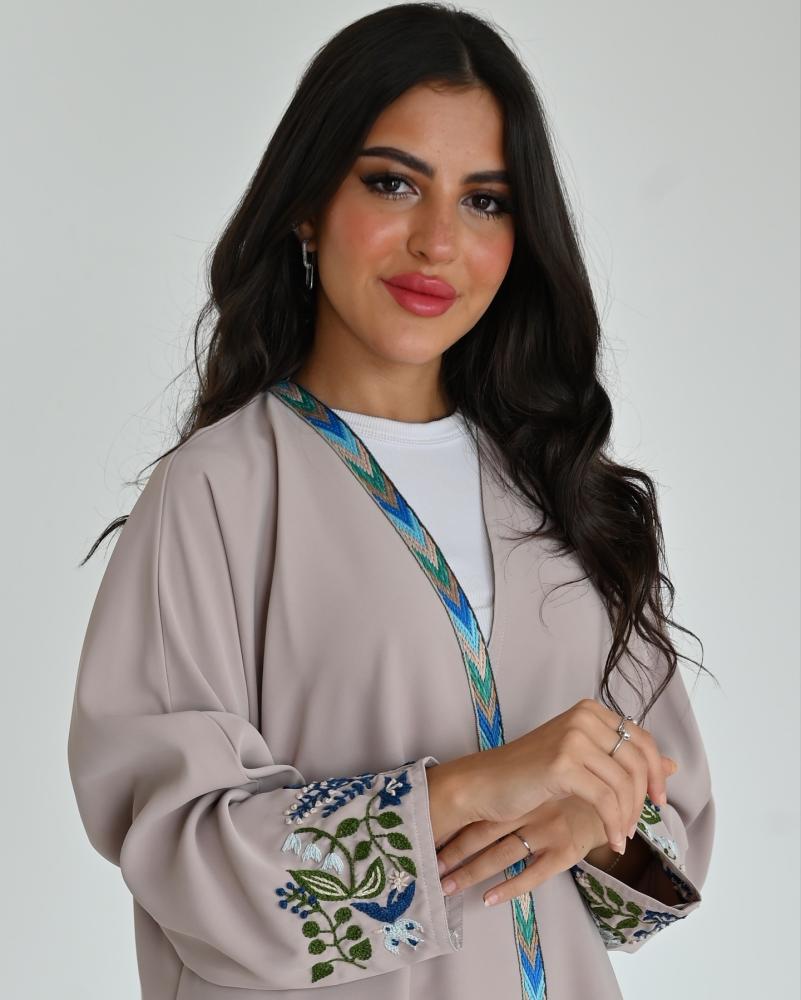 A washed silk fabric abaya in beige, decorated with hand embroidery on the sleeve, and a front panel with a quarter circle model.
