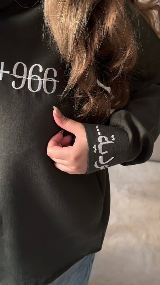 قميص اليوم الوطني السعودي زيتي بتصميم +966