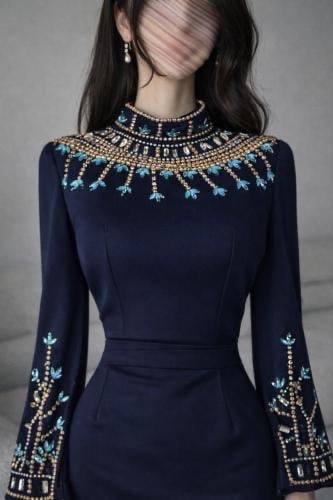 يظهر في الصورة فستان سهرة أو جلابية باللون الكحلي، تتميز بتصميم أنيق يتضمن تطريزاً يدوياً كثيفاً على شكل ياقة دائرية عريضة (عقد) وعند أطراف الأكمام الطويلة