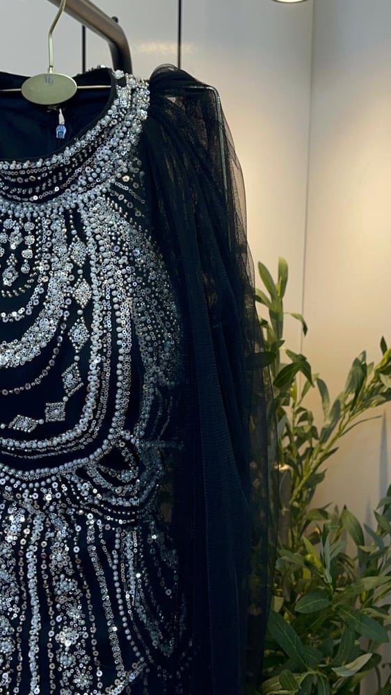 هذا الفستان هو فستان سهرة فاخر باللون الأسود، يتميز بتصميم مطرز بالكامل بالخرز والكريستال اللامع مع قصة انسيابية ووشاح من التول.