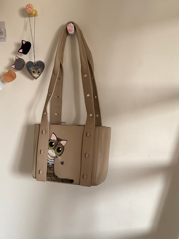 A beige leather bag with a cat design (a bag from the Saudi brand Zyrus)