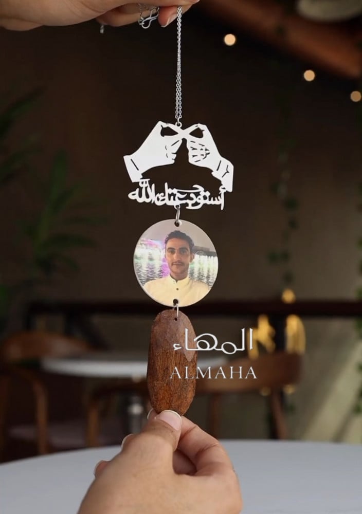 A pendant of two hands in the shape of infinity with a piece of oud