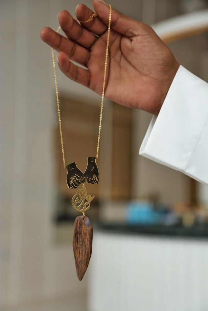 A pendant with carved hands holding each other's hands