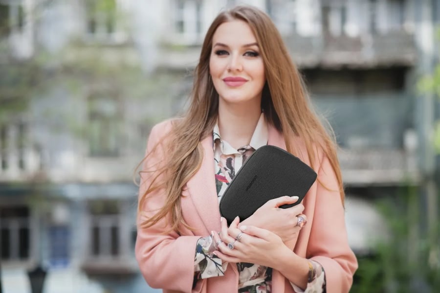 امرأة تحمل حقيبة سوداء صغيرة بأناقة