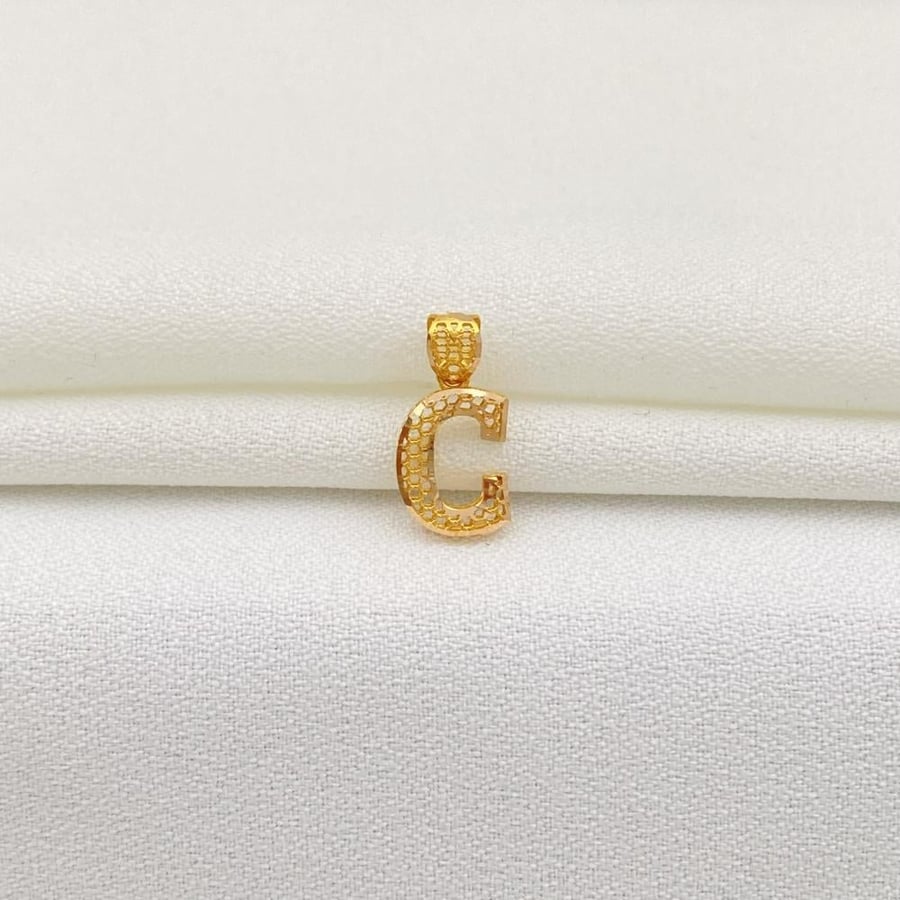 A pendant with the letter C, 21 karat gold, weighing 0.47 grams.