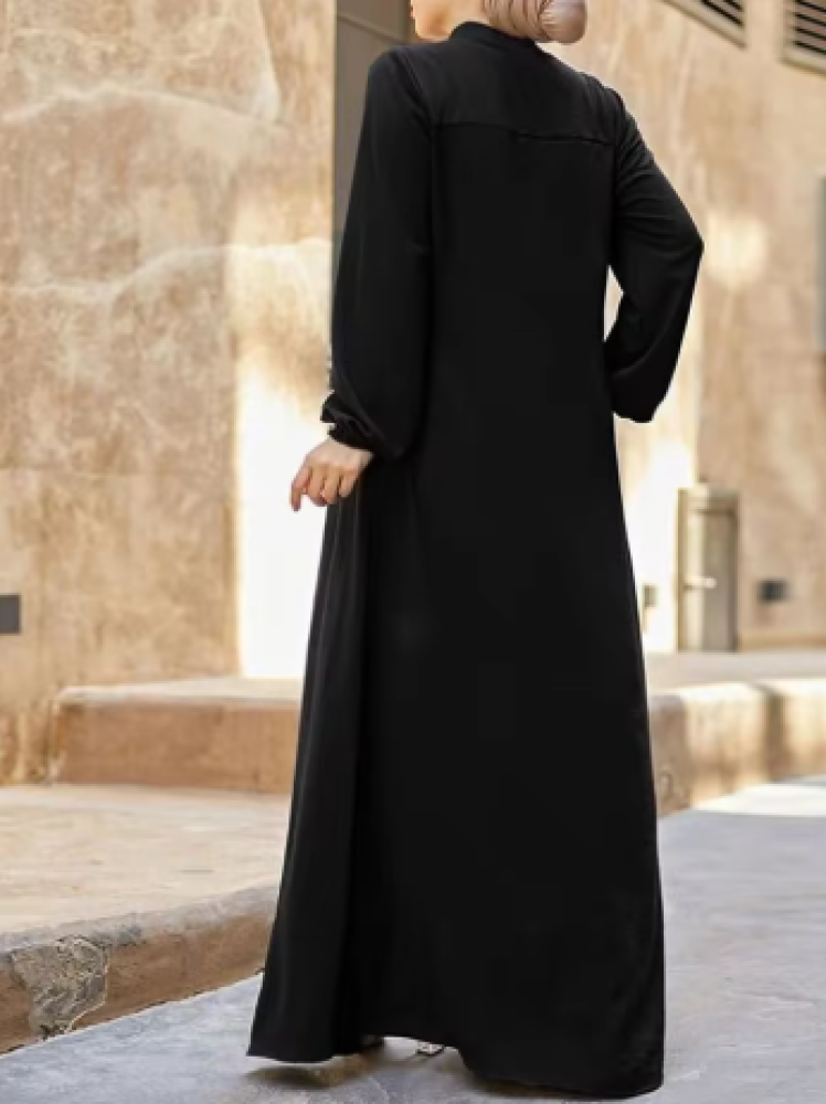 فستان أسود للمسلمات بتصميم أنيق وفضفاض وعصري، بياقة صغيرة قائمة وجيب بسحاب، بأكمام طويلة.