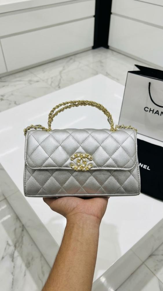 حقيبة يد نسائية من ماركة شانيل CHANEL صغيرة مبطنة باللون الأبيض مع سلسلة من الذهب.
