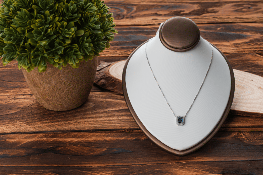 A necklace of white gold, adorned with diamonds, featuring a sapphire stone in the middle.