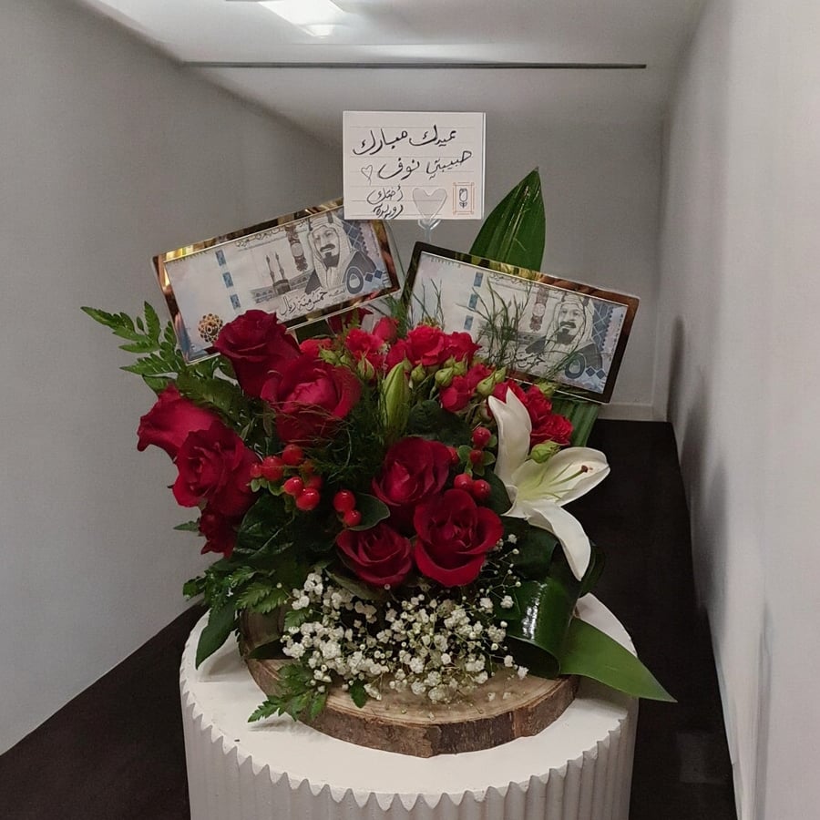 A bouquet of flowers on a base with a box and an acrylic watering can