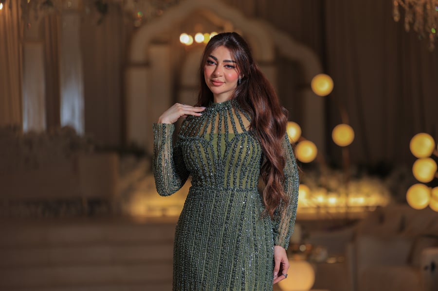 فستان أنيق وفاخر، يتميز بتصميم طويل بلون زيتي مائل للأخضر، مغطى بالكامل بتطريزات فاخرة لامعة بخطوط طولية