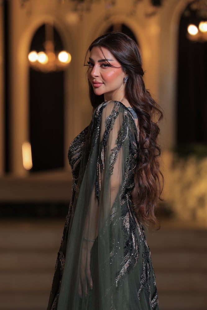 فستان سهرة فاخر وأنيق بتصميم راقٍ جدًا. لون الفستان زيتي ، ومزين بتطريزات لامعة من الخرز والترتر باللون الفضي المائل للذهبي