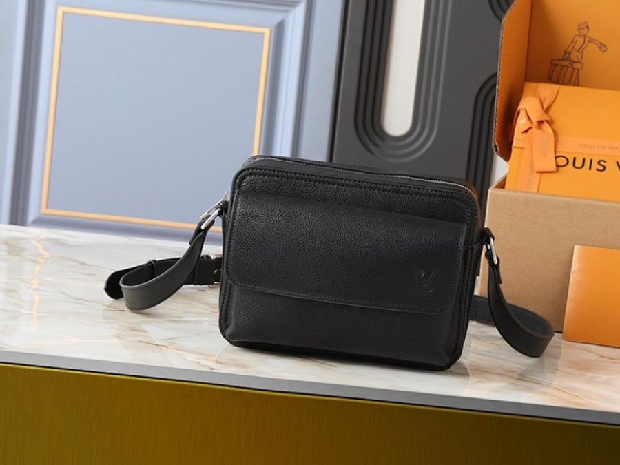 شنطة Louis Vuitton باللون الأسود بتصميم كروس صغير ونقشة Monogram، مع تفاصيل متباينة وإبزيمين بارزين في الواجهة. تصميمها المنظم وحزام الكتف الطويل يمنحانها مظهرًا عصريًا سهل التنسيق، بينما تضيف التفاصيل الأمامية لمسة لافتة تناسب الإطلالات اليومية بدرجاتها