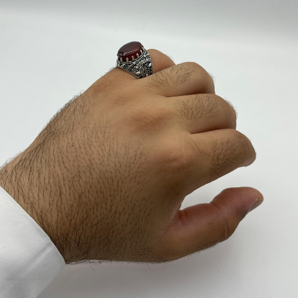 بالخنصر خاتم فضة متوج بالعقيق الأحمر الكبدي