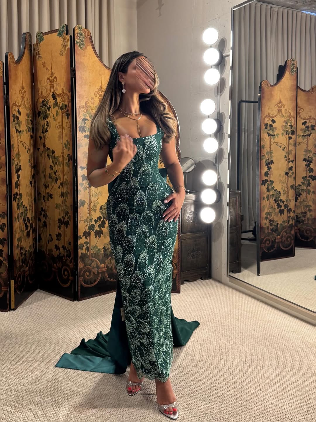 فستان سهرة طويل بلون أخضر زمردي، مزين بالكامل بالترتر أو الخرز اللامع بتصميم يشبه قشور السمك أو الريش