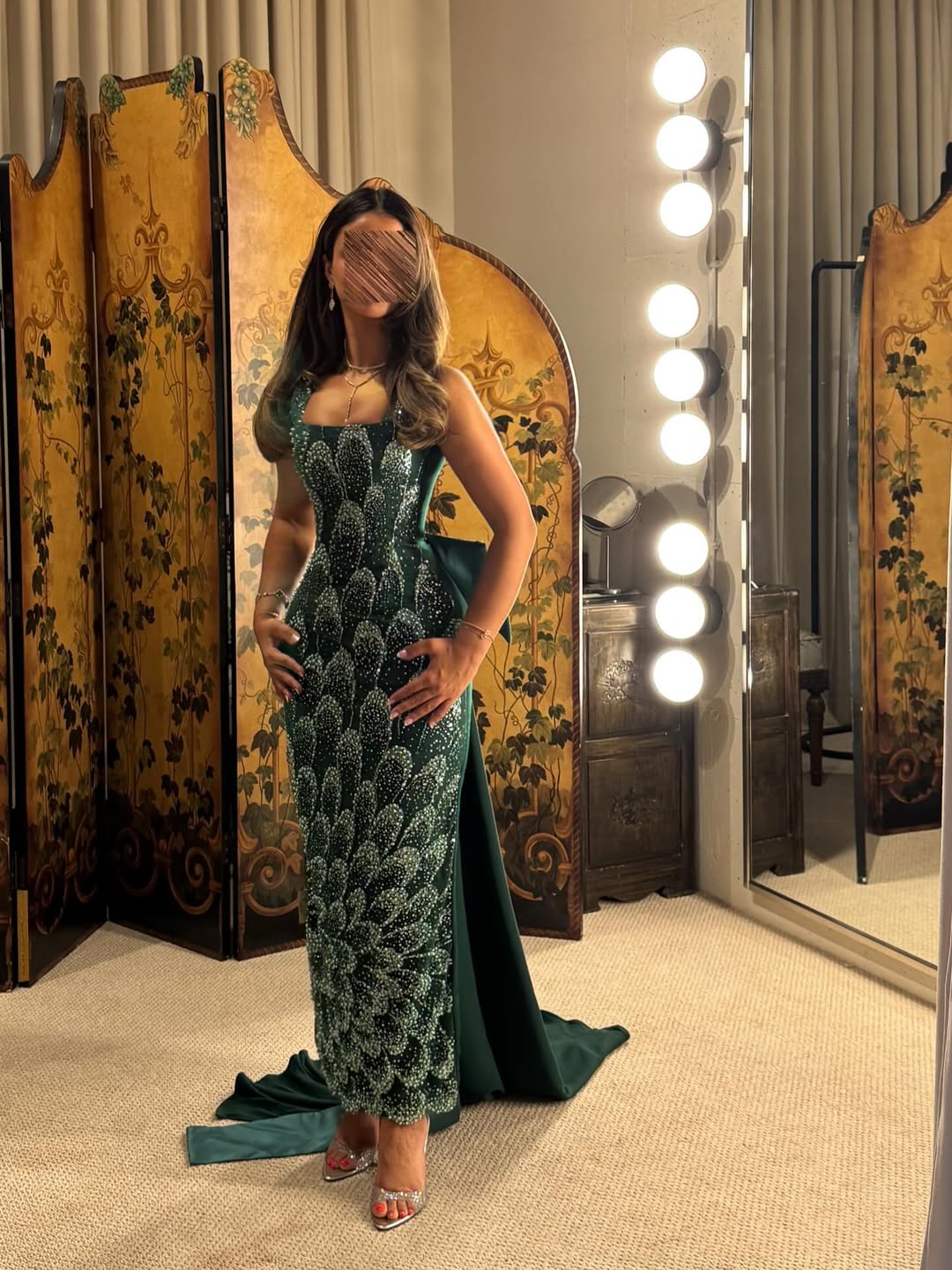 فستان سهرة طويل بلون أخضر زمردي، مزين بالكامل بالترتر أو الخرز اللامع بتصميم يشبه قشور السمك أو الريش