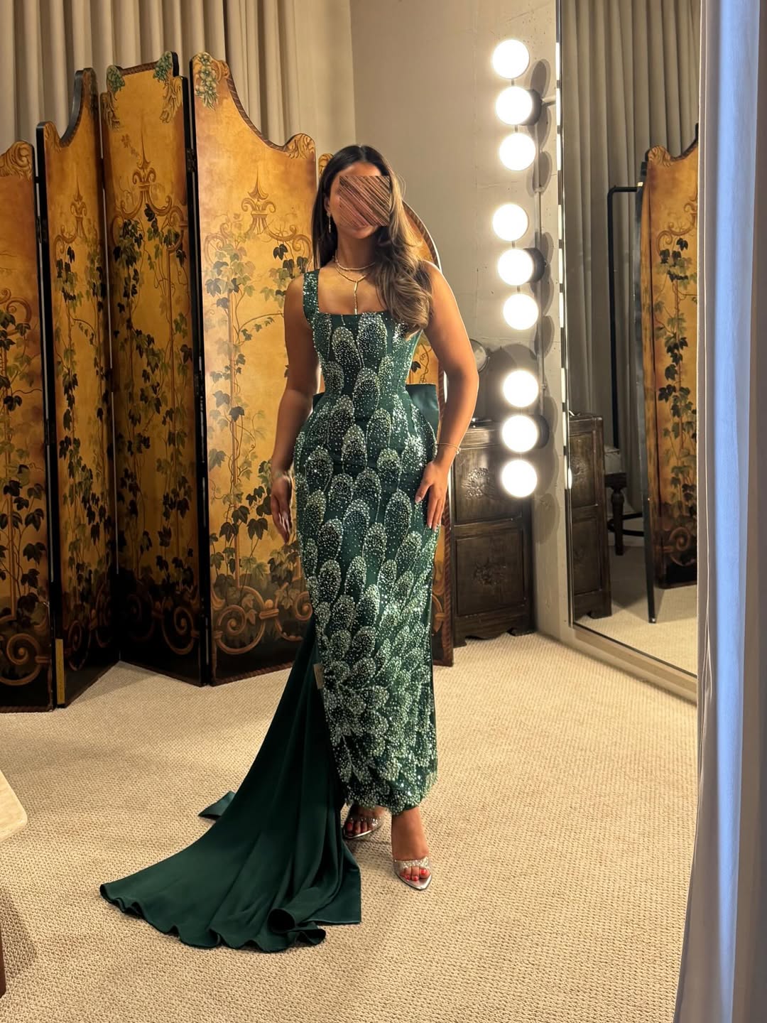 فستان سهرة طويل بلون أخضر زمردي، مزين بالكامل بالترتر أو الخرز اللامع بتصميم يشبه قشور السمك أو الريش
